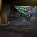 Scenic View from Stone Tunnel with Green Vegetation Stone Wall and Dirt Path
