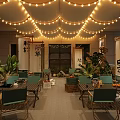 Japanese Outdoor Restaurant Dining Space With String Lights Scroll Decorations Green Plants And Wooden Tables