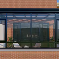 Glass Sunroom Attached To Red Brick Building With Black Frame And Glass Windows