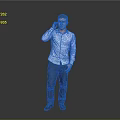 A Man Talking on the Phone in Blue Shirt and Dark Pants Against Gray Background