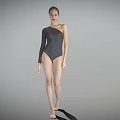 A Woman Wearing One Shoulder Gray Bodysuit Standing Barefoot Against Simple Gray Background