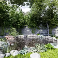 Tranquil Garden Landscape With Pond Stones Lush Trees Brick Wall And Stone Pathways