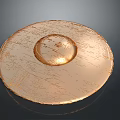 Golden Circular Textured Object with Raised Center and Metallic Surface on Dark Background