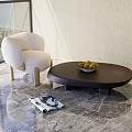 Modern Black Round Coffee Table with Fruit Bowl and Beige Chair on Marble Floor