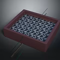 Red Square Box With Silver Ring Pattern And Metal Needles Arranged