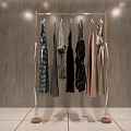 Golden Metal Clothes Rack With Hanging Clothes On Grey Wall White Tiled Floor