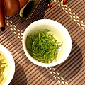 Traditional Tea Set With White Teacups Green Tea Leaves And Brown Teapot On Bamboo Mat