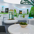 Modern Exhibition Hall Interior With Green Tree Shaped Decoration White Pendant Lights And Eco Counters