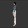 Woman in Green Lace Top and White Pants Standing Against Dark Background