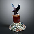 Eagle Sculpture Perched On Red Pillar With Colorful Stones At Base