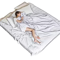 Woman Resting Comfortably On Bed With White Bedding And Pillows