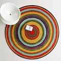Colorful Round Area Rug With Concentric Stripes And White Bowl On White Surface