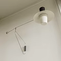 Modern Wall Lamp with Black Lampshade and Silver Curved Bracket on White Wall Near Curtains