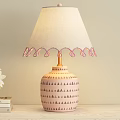 Table Lamp With Beige Fabric Shade Pink Tassels And Ceramic Striped Base On Wooden Table