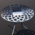 Round Metal Outdoor Table With Intricate Cutout Design And Laptop On Top