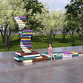 Campus Landscape Featuring Book Stacked Art Installation Lawn Trees And Colorful Seats With Students Reading