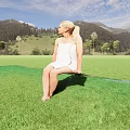 Woman In White Wrap Dress Sitting On Wooden Platform With Green Meadow Trees And Mountains