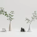 White Vases Holding Green Branches Alongside Books Elephant Figurine And Stone On Minimalist Gray Background
