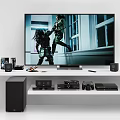 Large Screen Smart TV Showing Action Scene With Gaming Consoles And Sound System