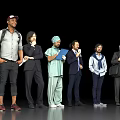 Group of People in Various Attires Standing Together With Different Items