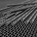 Thick Twisted Steel Rebars Neatly Stacked On Metal Mesh Grid Surface