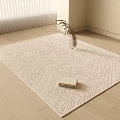 Light Beige Woven Square Rug With Herringbone Pattern On Wooden Floor Featuring Books And Vase