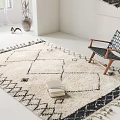 Square Cream Black Geometric Pattern Rug With Tassels And Woven Chair In Minimalist Room