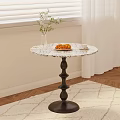 Marble Top Side Table with Black Spiral Base Holding Croissants Coffee and White Flower Vase