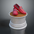 Red Loafers with Metallic Accents Displayed on White Pedestal with Wooden Top