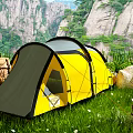 Yellow And Gray Camping Tent Set Up On Green Grassland With Mountain Rocks And Backpacks