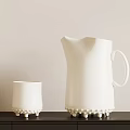 White Ceramic Cup And Pitcher With Pearl Like Bumps On Base On Dark Shelf