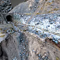 Stone Tunnel Entrance in Mountainous Terrain With Rocks Snow Patches and Slope Path