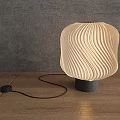 Modern Wavy Lampshade Table Lamp With Warm Light On Wooden Table Against Gray Wall
