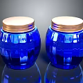 Two Carved Blue Glass Jars With Gold Lids And Intricate Sculpted Patterns