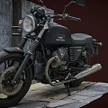 Vintage Black Motorcycle With Headlight Exhaust Pipe Parked On Stone Pavement Near Gray Wall
