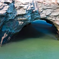 Scenic Natural Rock Arch Formation Over Calm Green Coastal Water