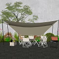 Outdoor Table And Chair Set With Canopy Grill And Green Plants On Stone Patio