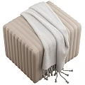 Black and Beige Vertical Pleated Ottomans Featuring Gray Blanket and Tassel Accents