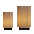 Two Hexagonal Table Lamps With Beige Fabric Shades And Black Bases Emitting Warm Light
