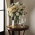 Vase with White and Yellow Flowers on Wooden Table with Petals Tall Glasses and Card