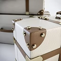 White Suitcases With Brown Straps And Metal Buckles Stacked Together