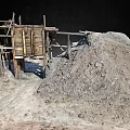 Rugged Landscape Featuring Old Wooden Shed Sand Pile On Barren Ground Under Dark Sky