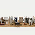 Various Colored Books On Wooden Table With Decor Items Including Dried Flowers Small Ornaments