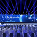 Large Event Venue With Blue Lighting Stage Backdrop Screen And Arranged Chairs