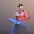 Man in Red Hoodie and Blue Jeans Holding White Cup Sitting Smiling and Gesturing