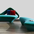 Teal Curved Sofa with Red and Blue Pillows and Matching Ottoman on Wooden Floor