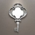 Golden Key Shaped Decorative Mirror With Ornate Frame Hanging On Gray Wall