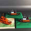 Orange Yacht Models With White Upper Structure Displayed On Green And Beige Bases
