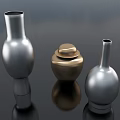 Ceramic Vessels Including Golden Lidded Jar And Silver Spherical Vases On Dark Reflective Surface