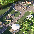 Rural Landscape Featuring Winding Stone Pathways Lush Lawn Stone Walls Wooden Tables And White Umbrella